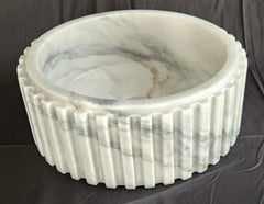 Marble basin with ribbed design on a dark background