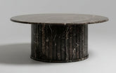 Round marble table with a dark, veined surface on a white background