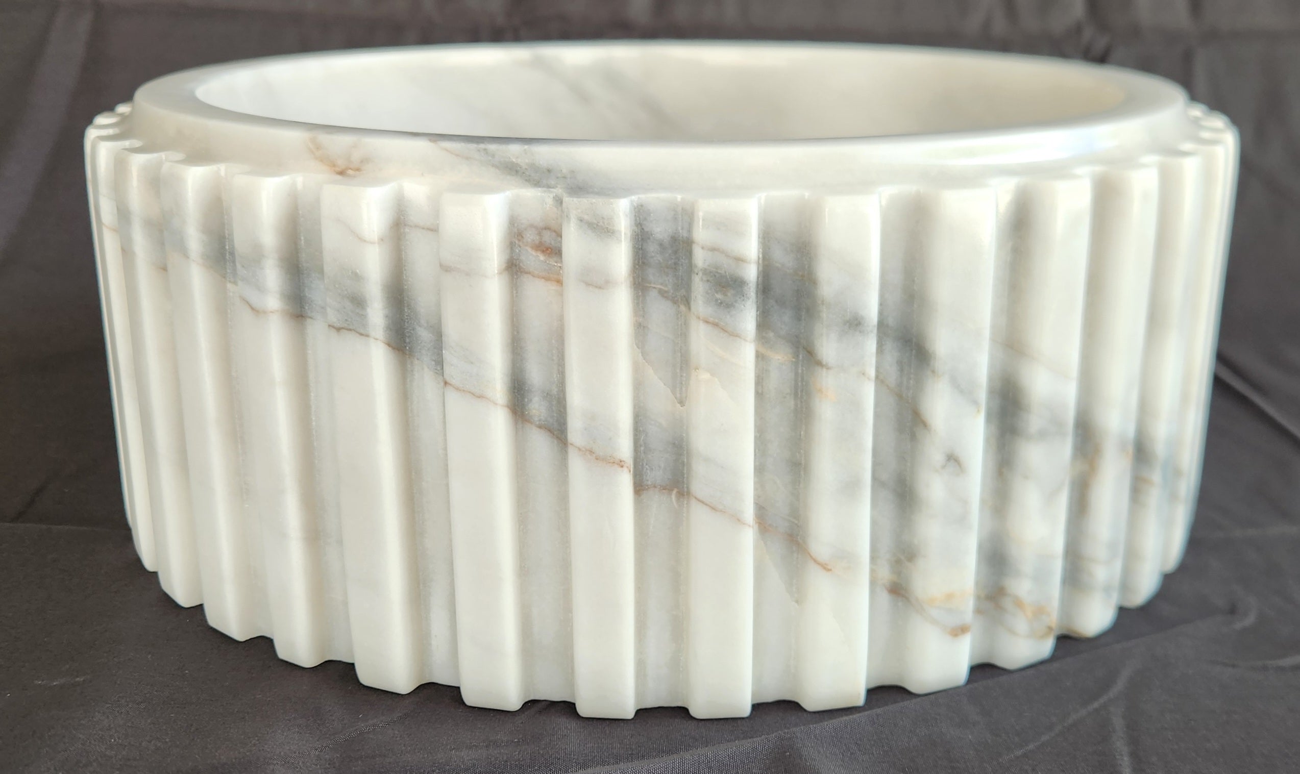 Marble basin with ribbed design on a dark background