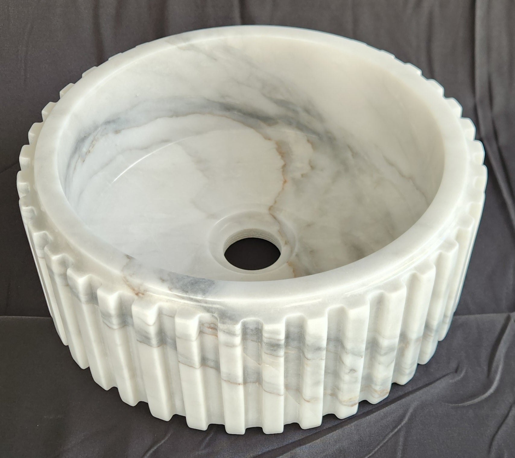 Marble sink with ribbed design on a dark background