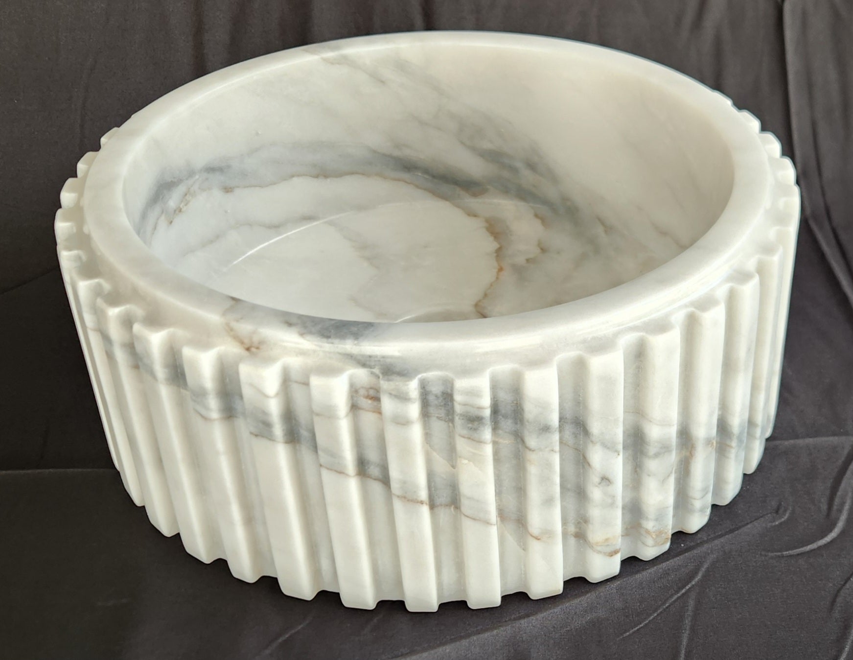 Marble basin with ribbed design on a dark background