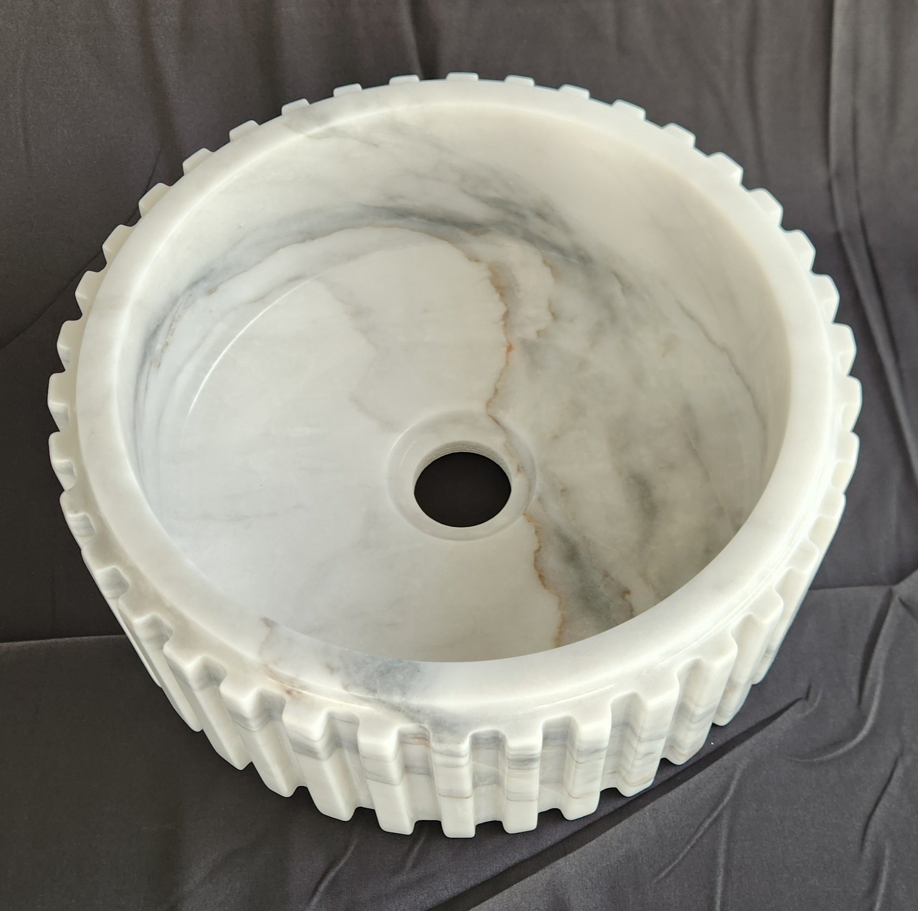 Marble sink with gear-like design on a dark background