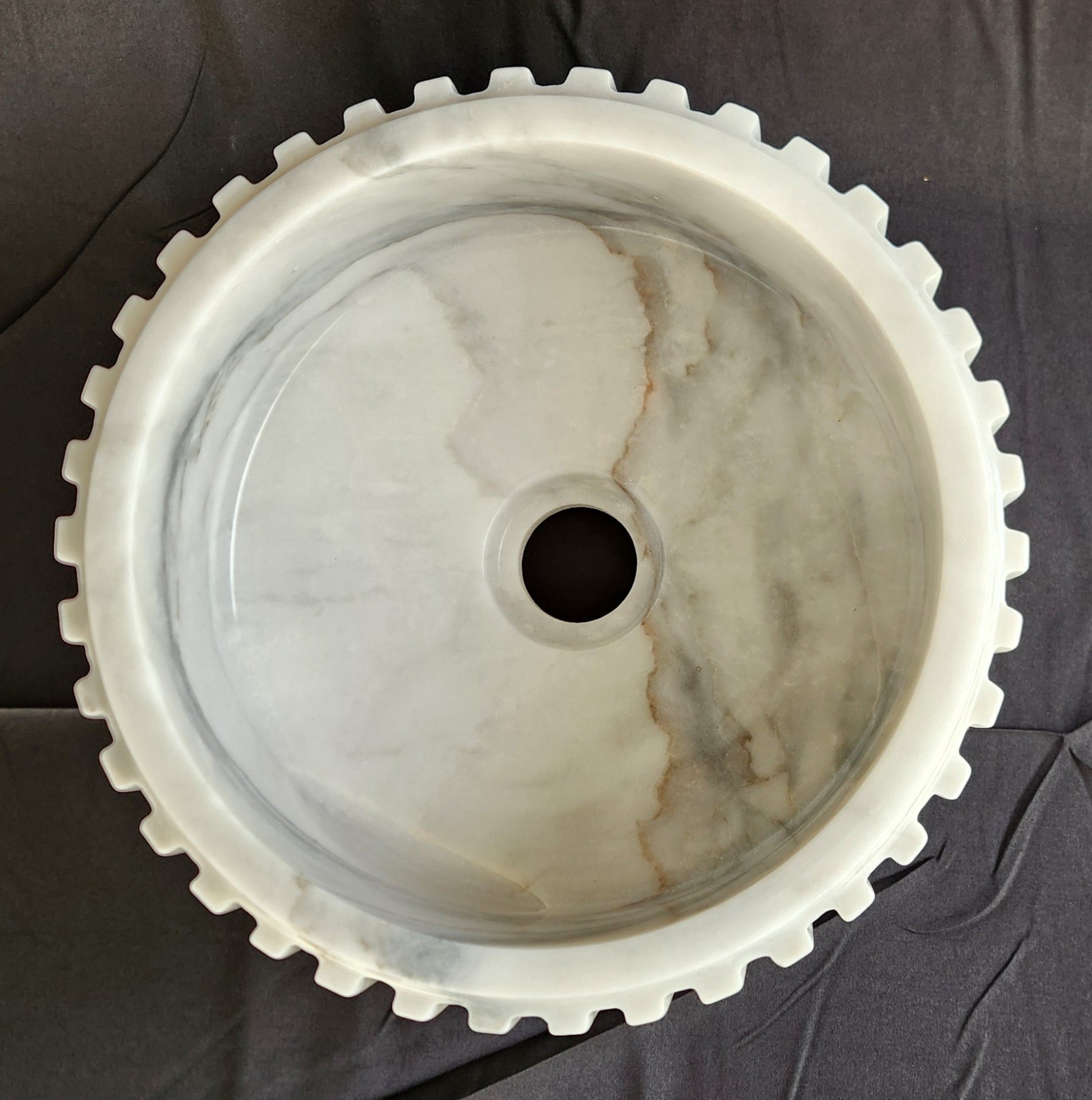 Marble-patterned sink with gear-like design on a dark background