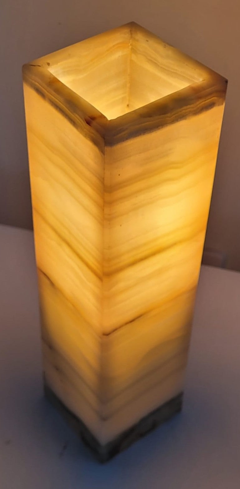 Square-shaped natural stone lamp with a warm glow on a neutral background